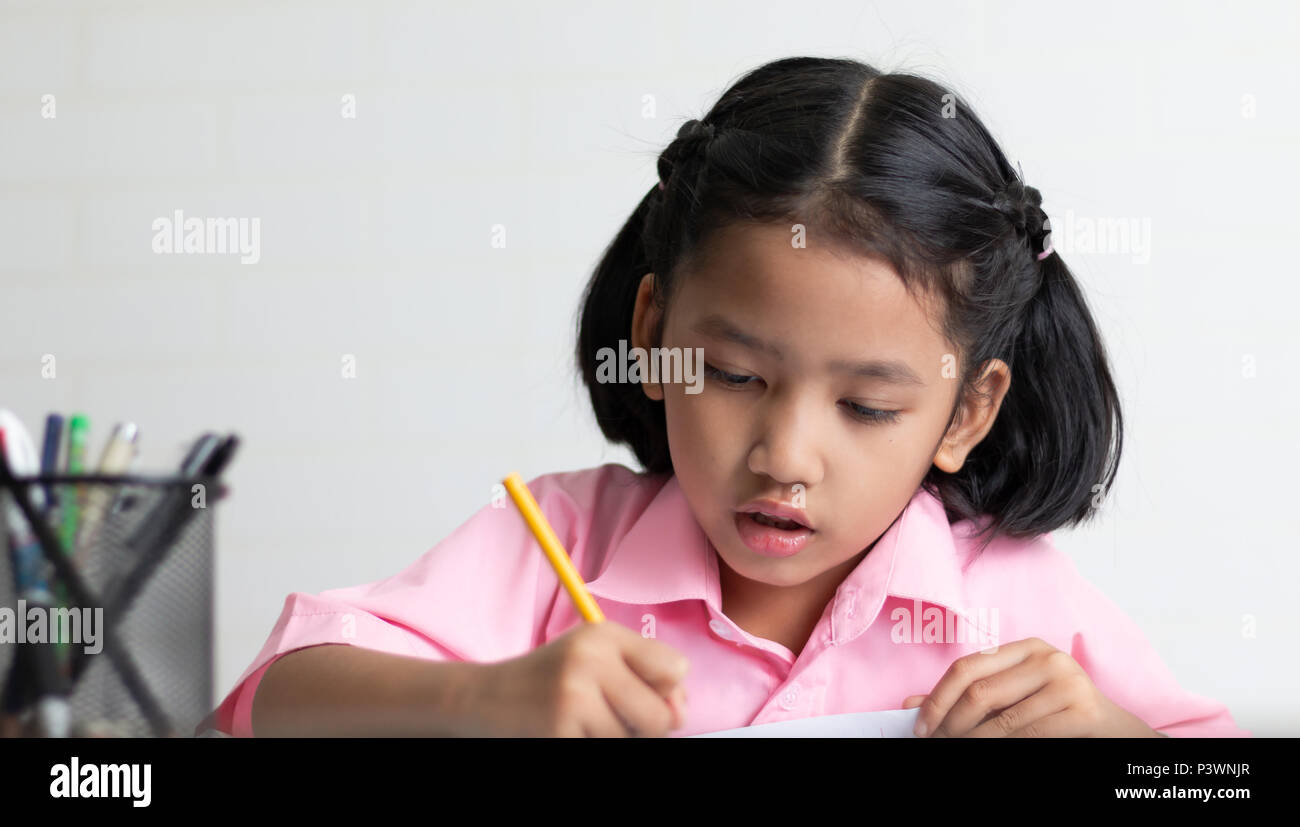 Chiudere la bambina è studiare attentamente. I bambini utilizzano una matita gialla è la scrittura di un notebook. Selezionare la messa a fuoco la profondità di campo di una copia con Foto Stock