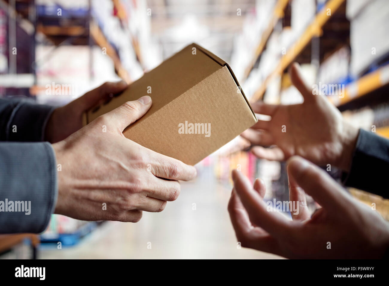 Lavoratore dando un pacchetto nel magazzino di distribuzione Foto Stock Lavoratore dando un pacchetto nel magazzino di distribuzione Foto Stock