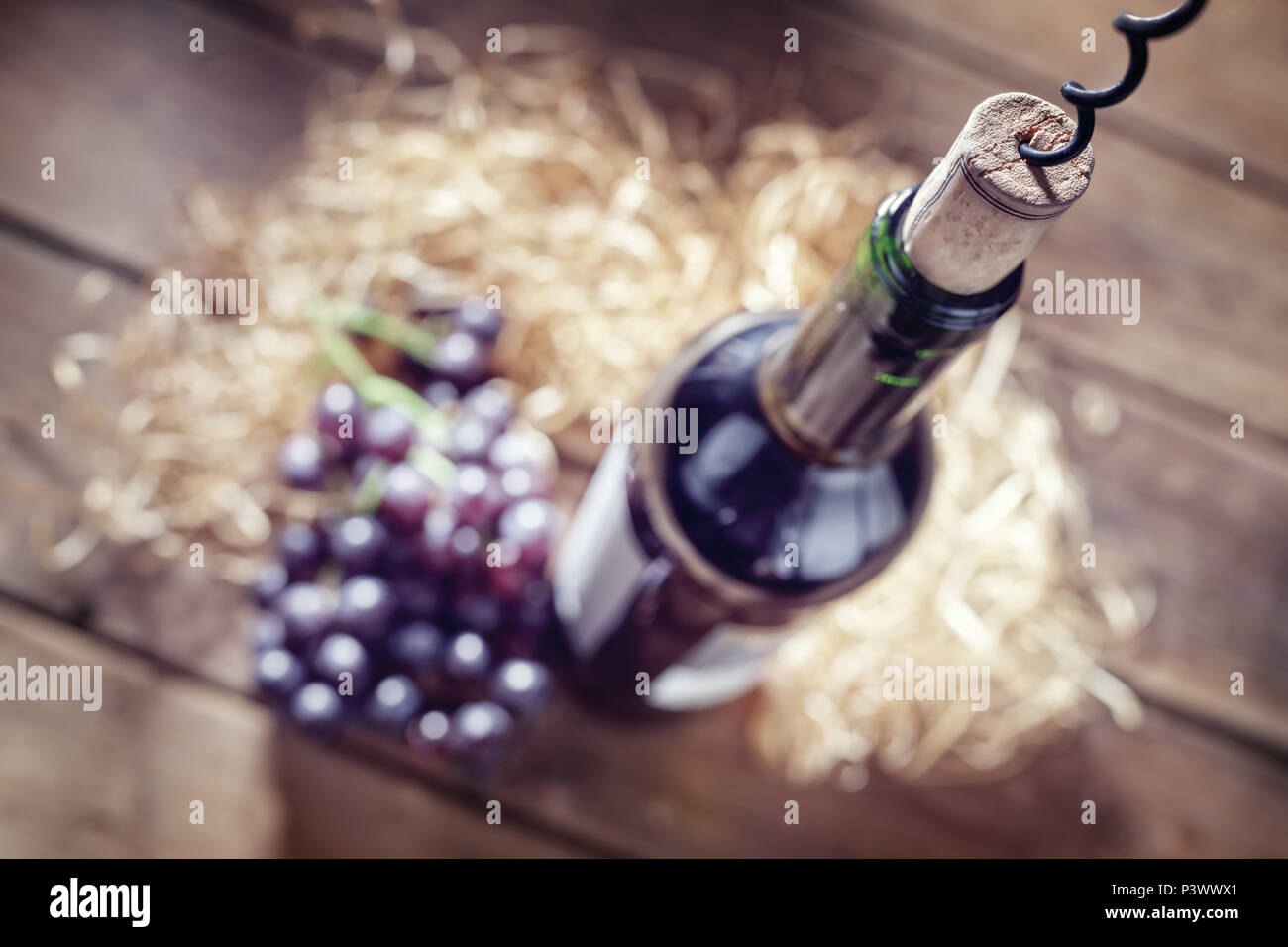 Bottiglia di vino, uva, sughero e cavatappi sul tavolo di legno Foto Stock