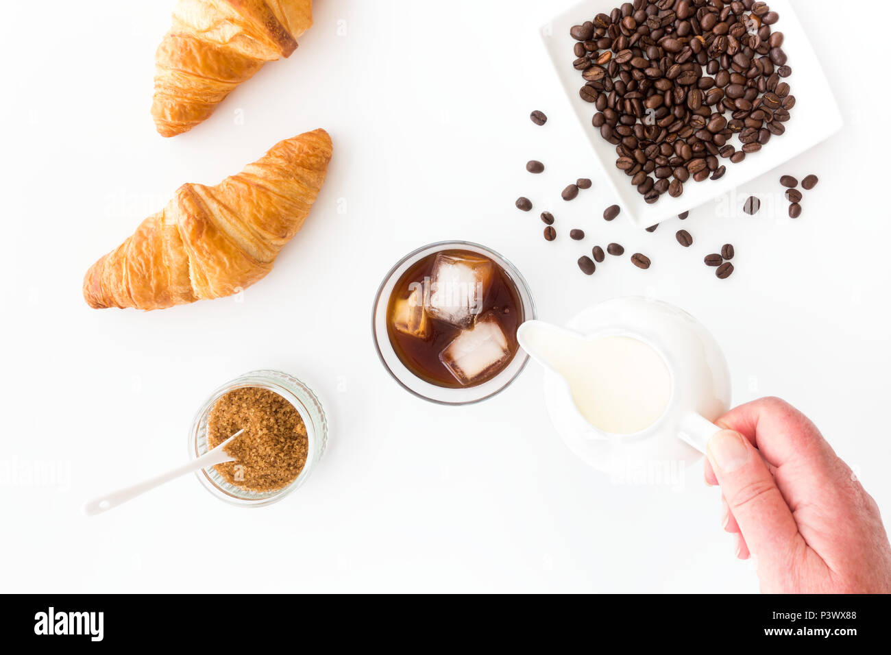 Mano versare il latte in un bicchiere di birra fredda caffè. Foto Stock