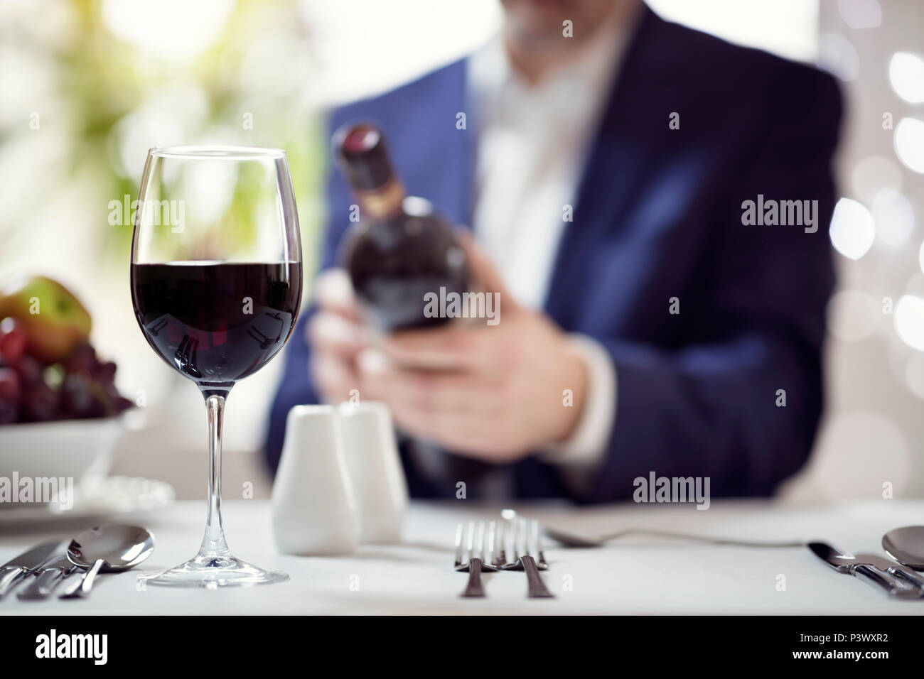 Imprenditore lettura vino rosso etichetta del flacone nel concetto di ristorante per pranzi di lavoro o cene incontro Foto Stock
