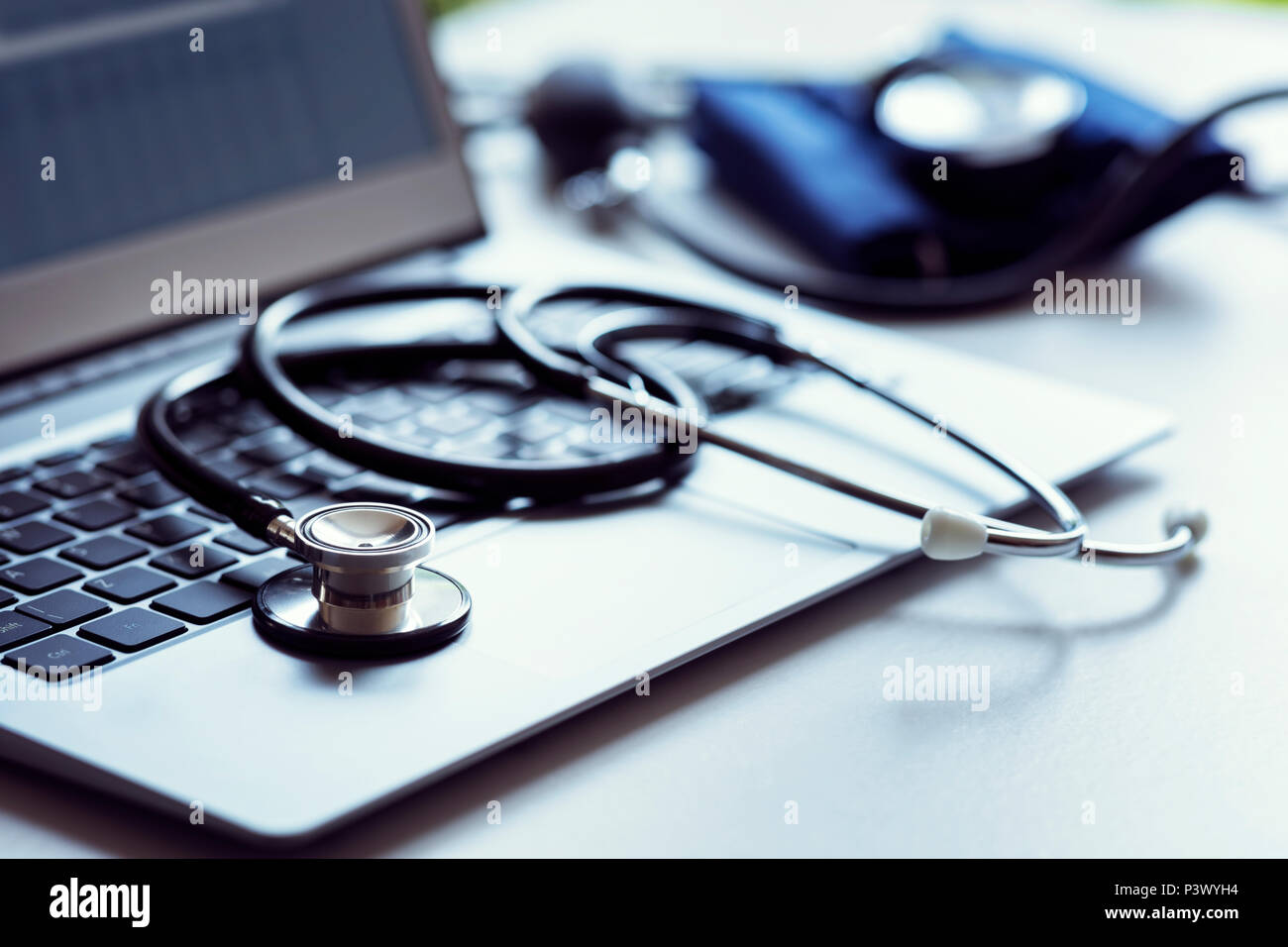 Lo stetoscopio sulla tastiera del notebook in ambulatorio medico con il monitor della pressione del sangue Foto Stock