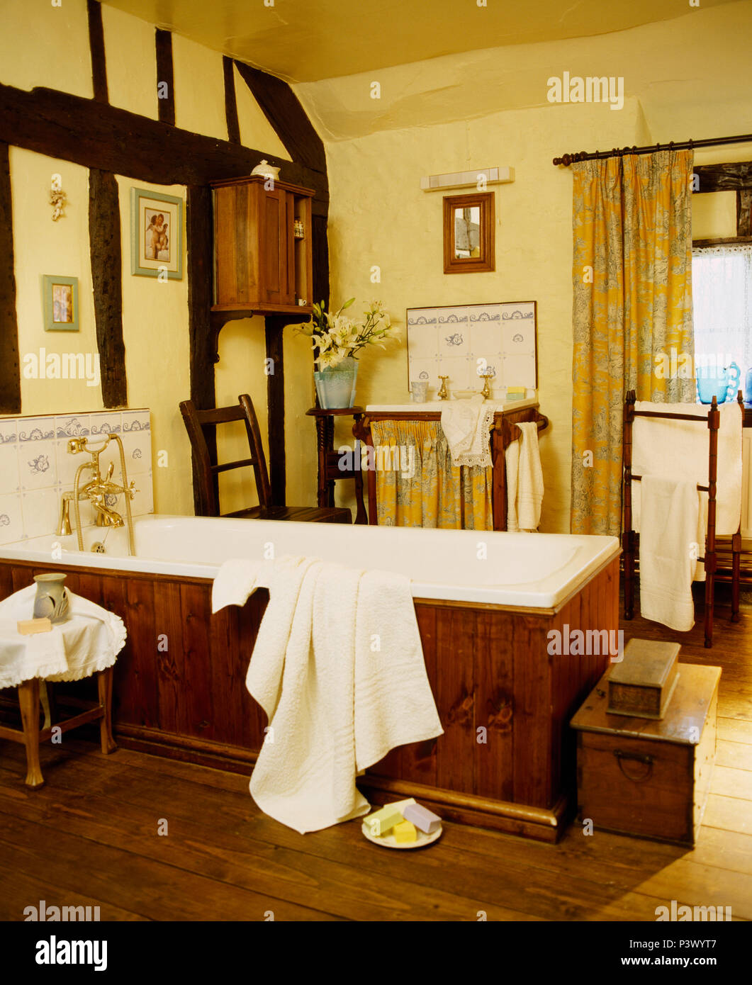 Grande stanza da bagno di colore giallo con visibile tinto scuro travi e accessori antichi Foto Stock
