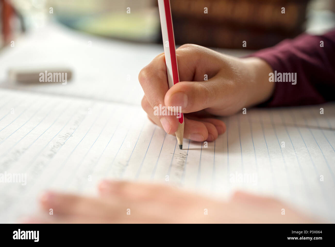 Ragazzo iscritto in un blocco note facendo il suo lavoro scolastico di ortografia o di compiti Foto Stock