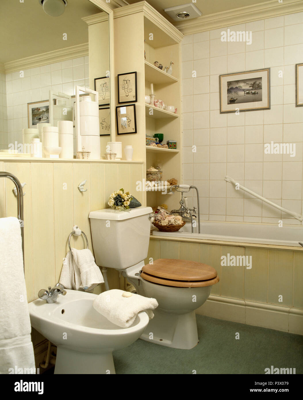 Bidet e wc con sedile in legno sotto lo specchio in bagno con il corrimano sopra vasca da bagno Foto Stock