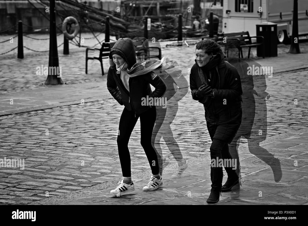 Esposizione multipla immagine monocromatica di due donna combattendo la testa sulla tempesta contro la forza dei venti. Foto Stock