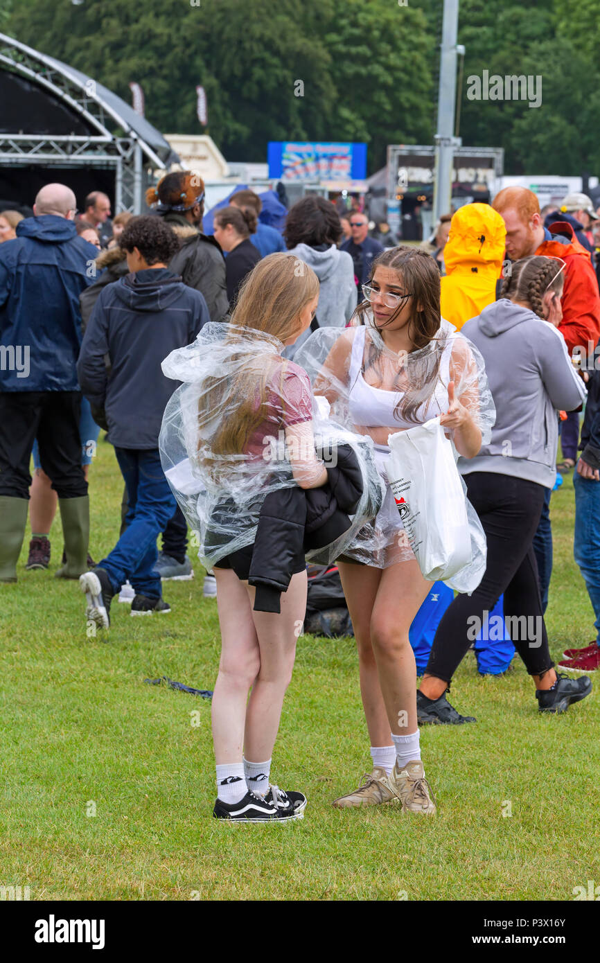 Due ragazze che indossano i Mac di plastica durante una doccia a pioggia il primo giorno dell'Africa Oye Music Festival di Sefton Park Liverpool 2018. Foto Stock