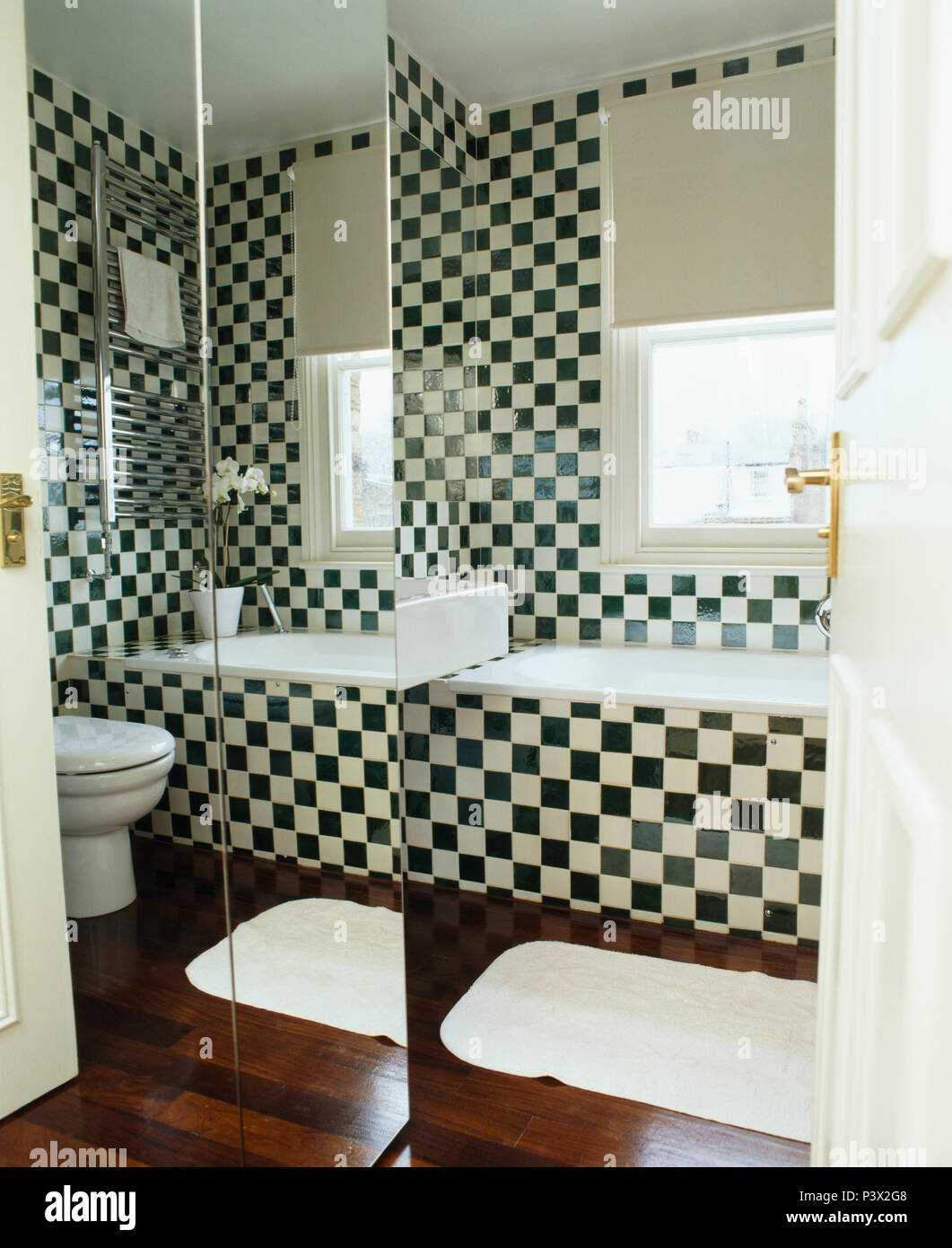 Parete specchiata in bagno moderno con nero+white chequerboard piastrelle Foto Stock