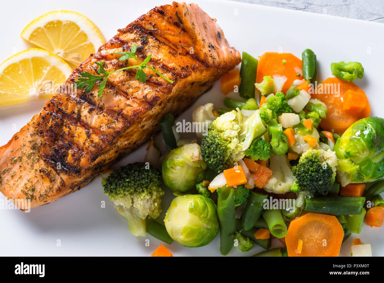 Salmone alla griglia filetto di pesce con verdure mix su piastra bianca. Close up. Foto Stock