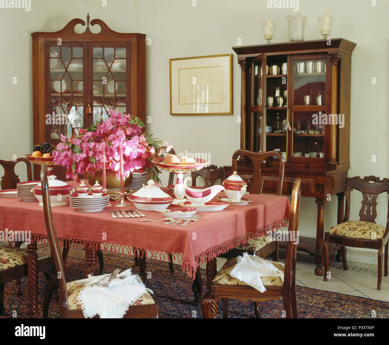 Vaso di fiori di colore rosa sul tavolo con un panno rosa fmettere o pranzo in Portoghese tradizionale sala da pranzo con armadi antichi Foto Stock