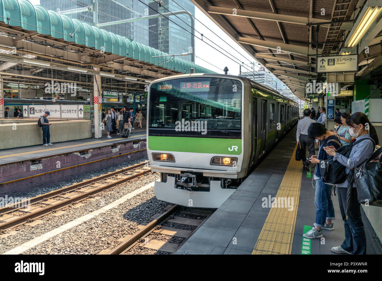 TOKYO, Giappone 22/05/2018: treno in arrivo presso la stazione dei treni mentre ci sono persone in attesa e guardando il loro smartphone Foto Stock
