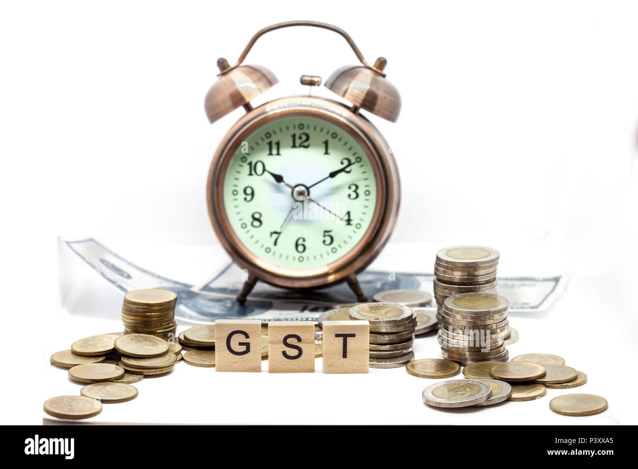 Beni e servizi fiscali sulla parola sveglia e pile di monete sul tavolo bianco, il successo nel business del concetto. Foto Stock