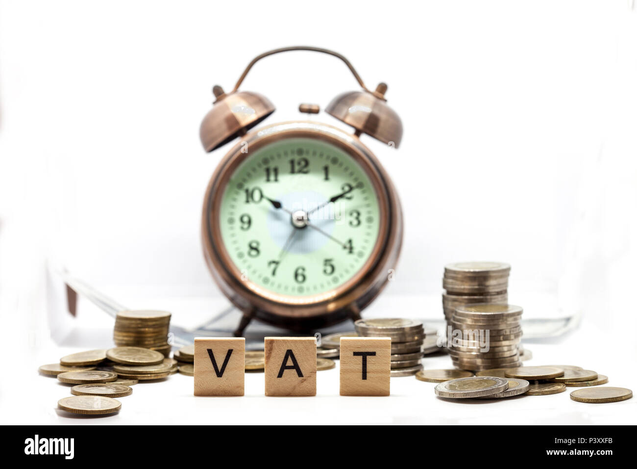 Beni e servizi fiscali sulla parola sveglia e pile di monete sul tavolo bianco, il successo nel business del concetto. Foto Stock