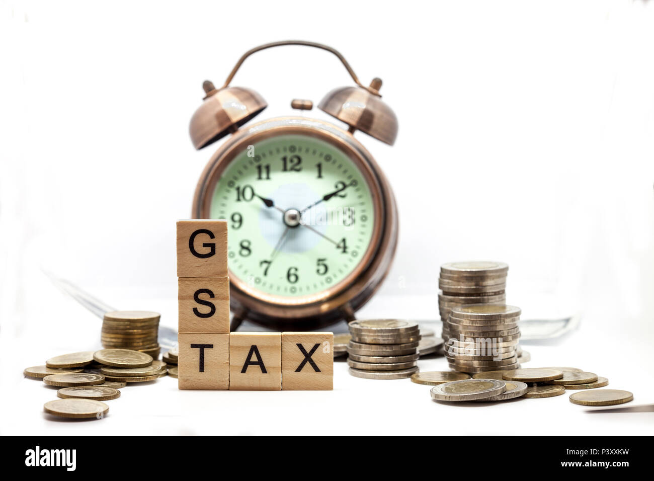 Beni e servizi fiscali sulla parola sveglia e pile di monete sul tavolo bianco, il successo nel business del concetto. Foto Stock