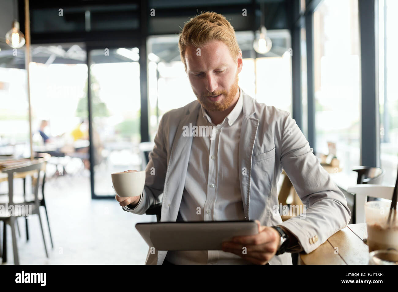 Imprenditore occupato bere un caffè mentre sono online Foto Stock