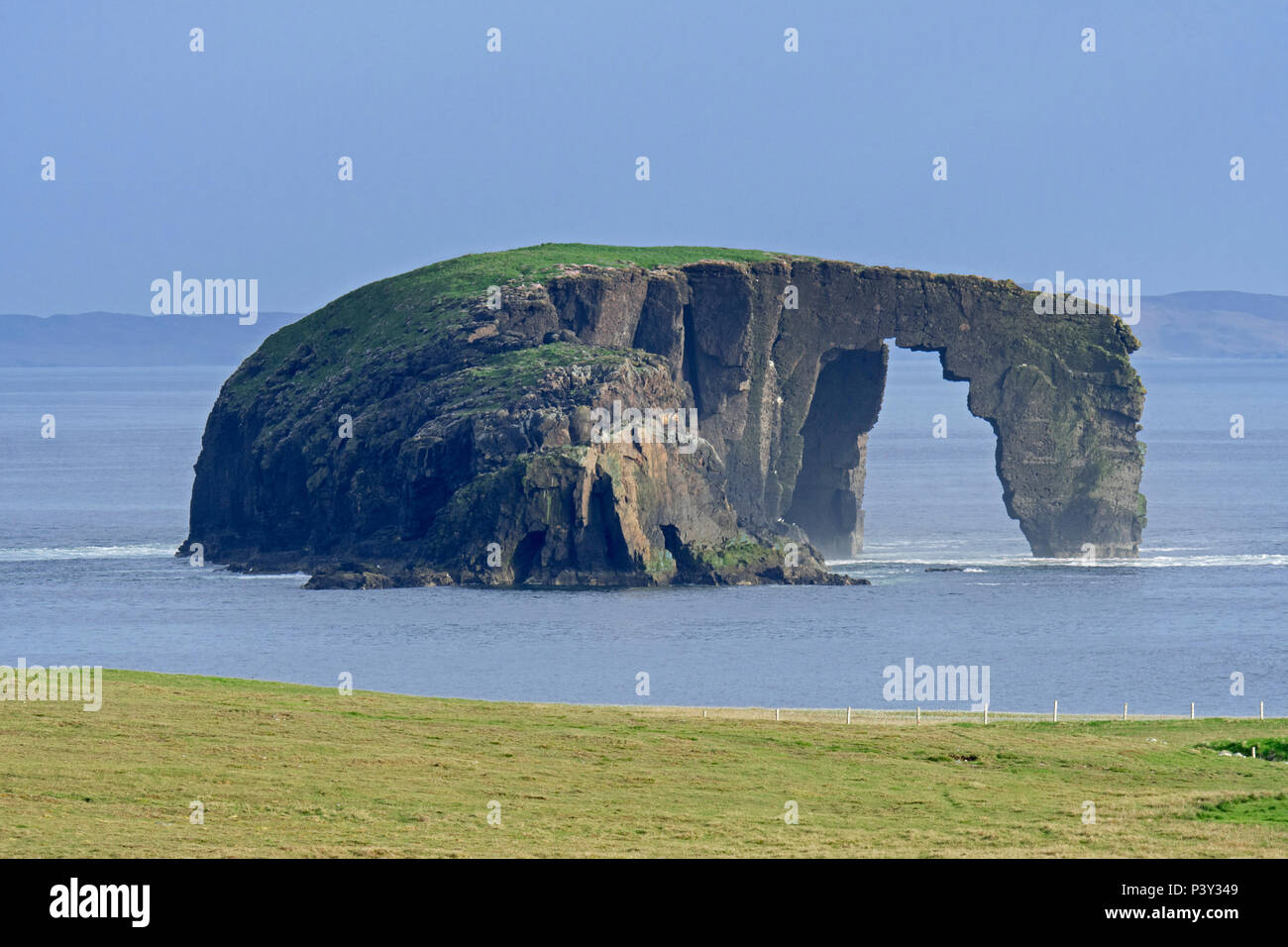 Dore Holm, piccolo isolotto con arco naturale al largo della costa di Stenness, Esha Ness / Eshaness sulla terraferma Shetland, Scotland, Regno Unito Foto Stock