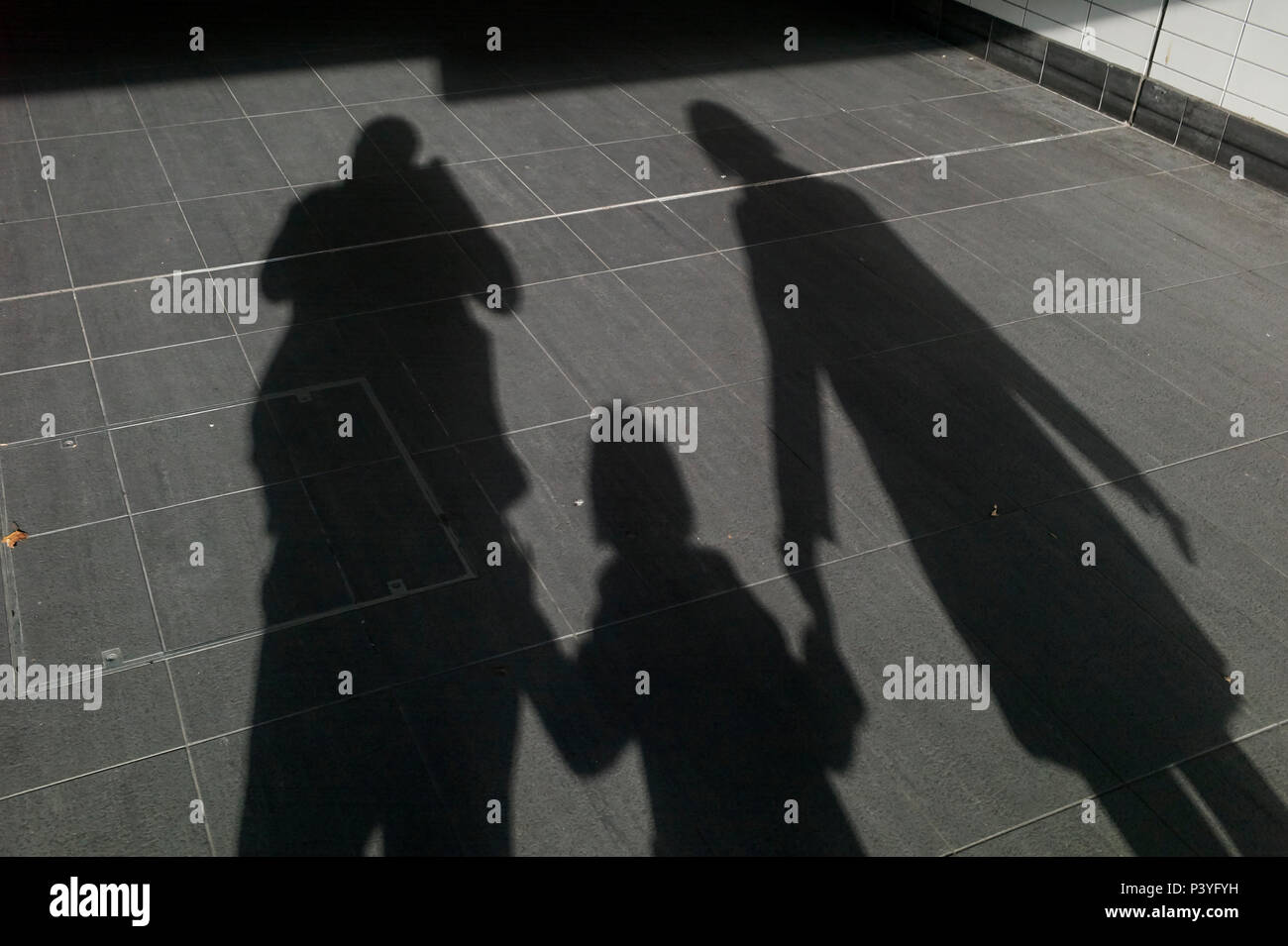 Madre padre e figlia in silhouette tenendo a piedi lettura vicino stazione ferroviaria. Foto Stock