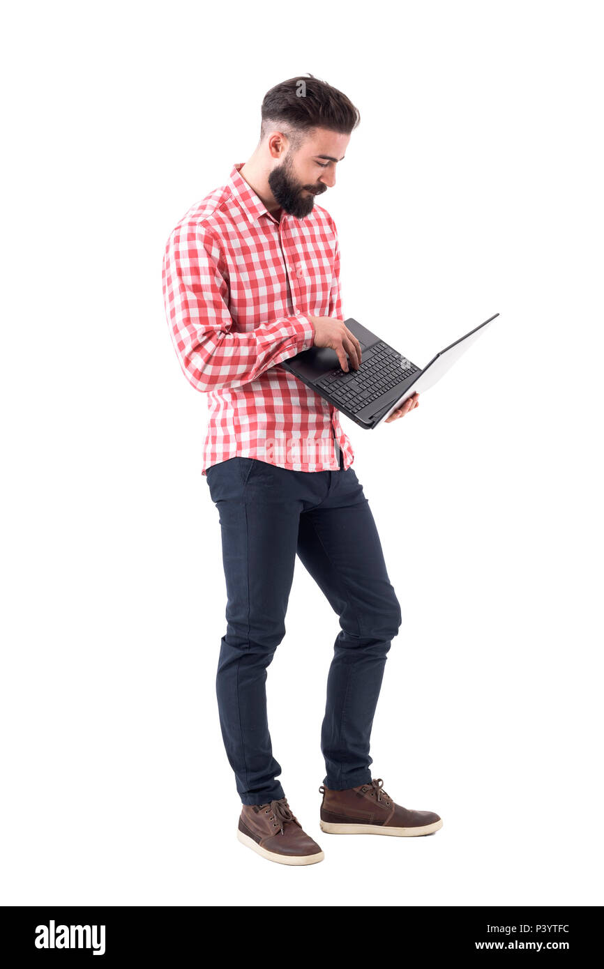 Barbuto moderno tanga millenario uomo di affari e di lavoro utilizzando il computer portatile. A piena lunghezza isolati su sfondo bianco. Foto Stock