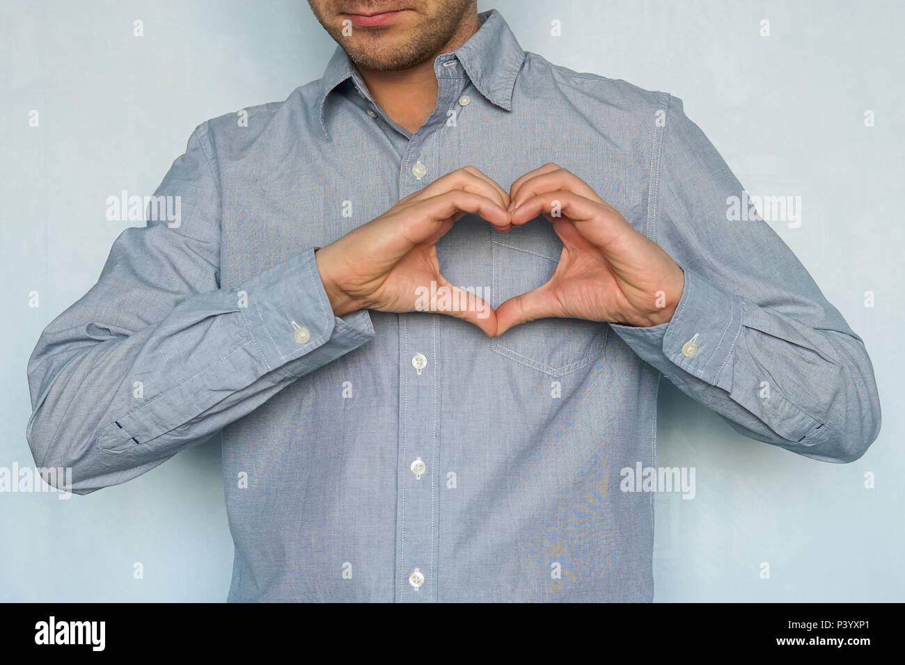 Una dichiarazione di amore. Il giorno di San Valentino. Felice uomo bello rendere cuore con le dita. Un giovane uomo in amore mostra i suoi sentimenti Foto Stock
