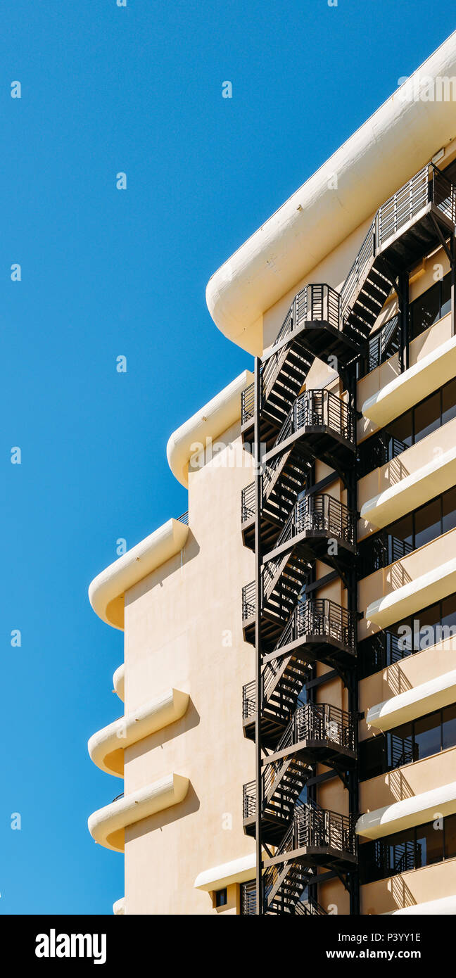 Metal fire escape sulla facciata di un edificio moderno con cielo blu Foto Stock