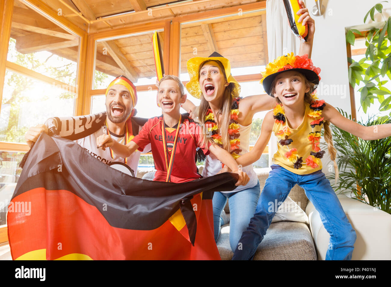 Tutta la famiglia il tifo per il calcio tedesco team nella parte anteriore della TV Foto Stock