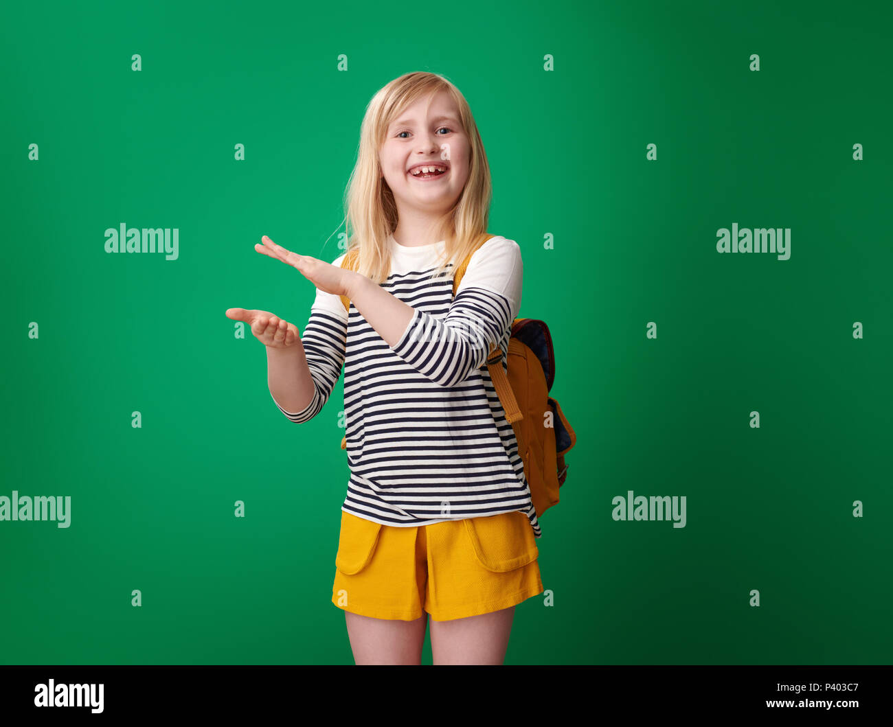 Scuola sorridente ragazza con zaino battimani isolati su sfondo verde Foto Stock