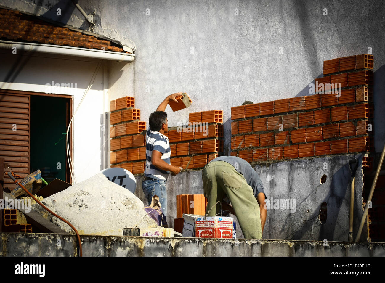 Pedreiros em construção levantando parede de tijolos. Foto Stock