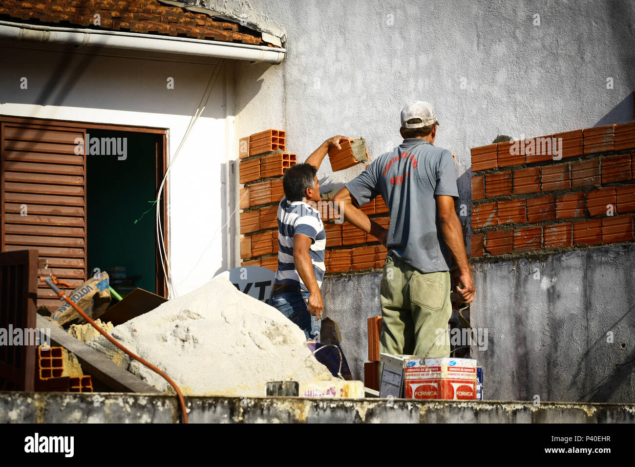 Pedreiros em construção levantando parede de tijolos. Foto Stock