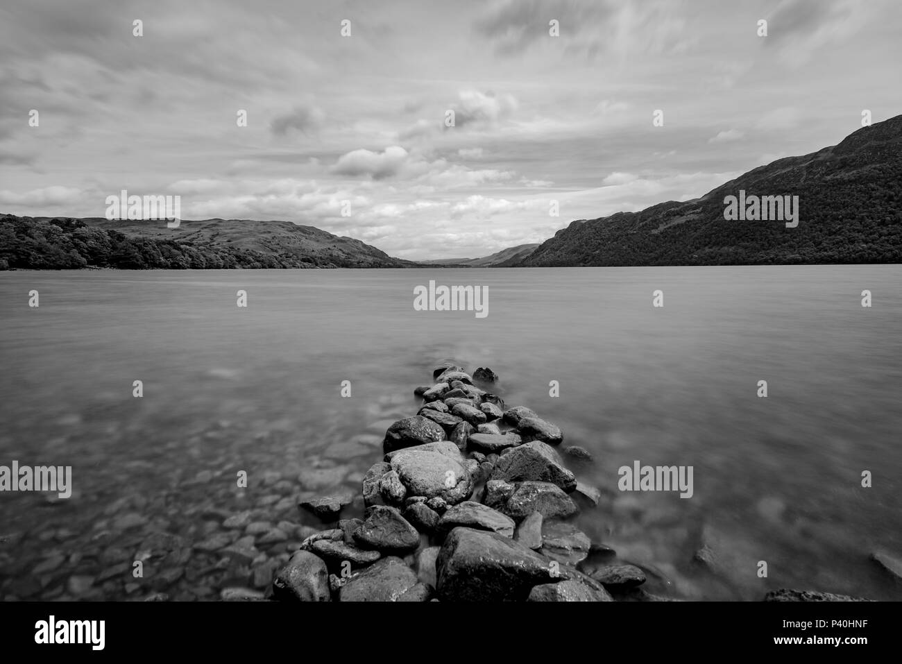 Un bianco e nero panorama di un lago con una collezione di rocce che conduce all'acqua. Foto Stock