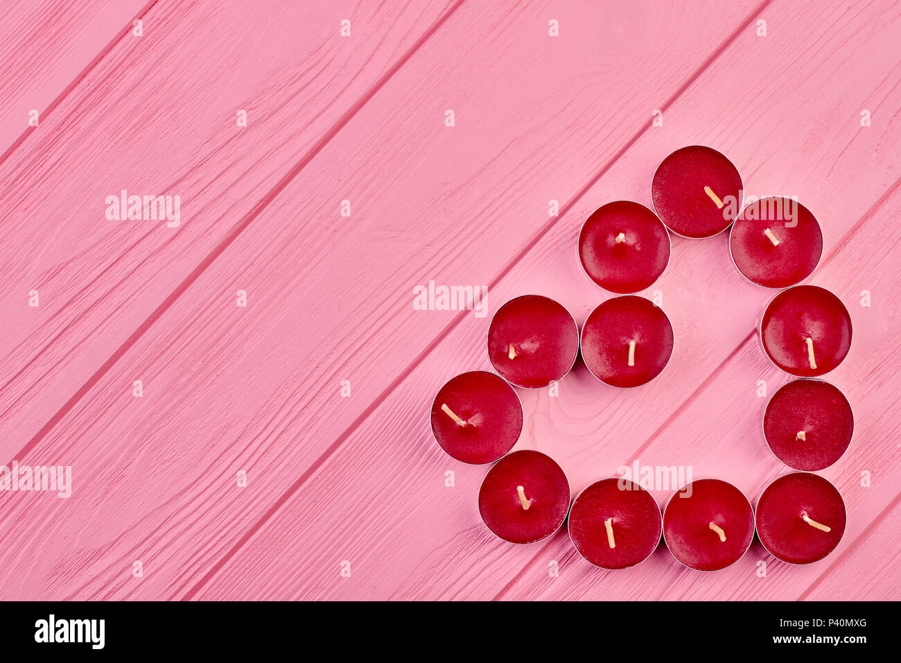 Luce di tè candele formando forma di cuore. Forma di cuore fatta di rosso le candele profumate rosa su sfondo di legno con copia spazio, vista dall'alto. Foto Stock