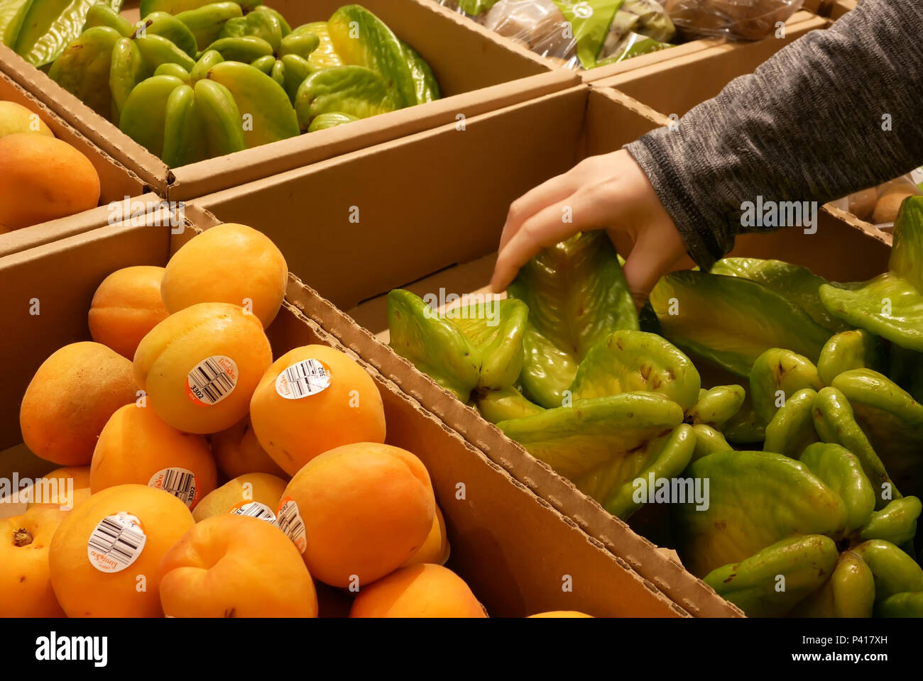 Movimento della donna di raccolta a mano starfruit all'interno di superstore Foto Stock