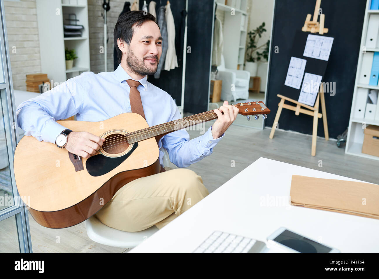 Uomo bello enjoyin chitarra in ufficio Foto Stock