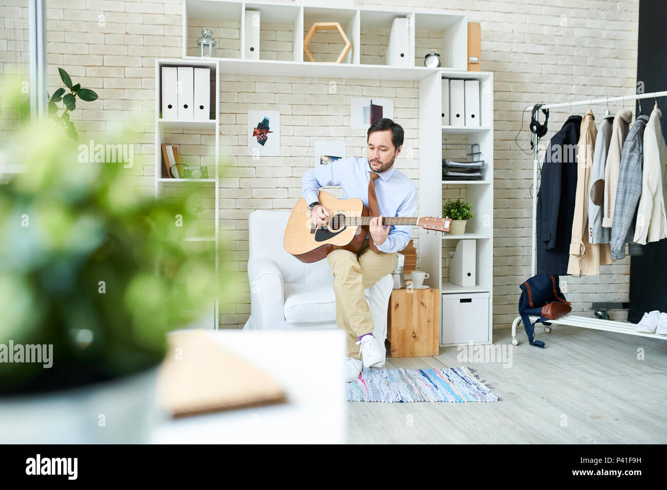 Alla moda uomo a suonare la chitarra in studio Foto Stock