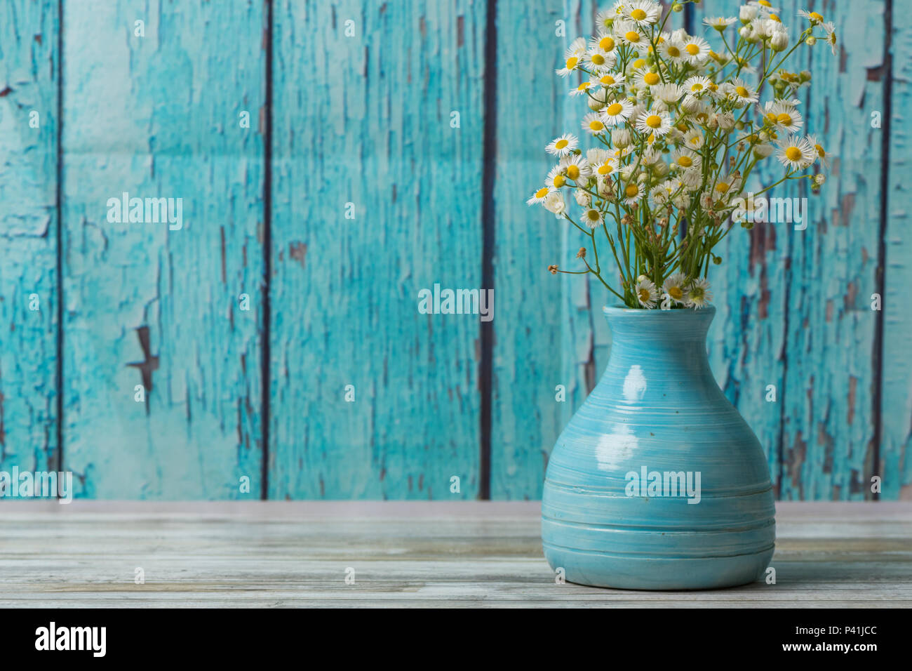 Bouquet di fiori in un vintage vaso blu con vernice pelata sullo sfondo di legno. Foto Stock