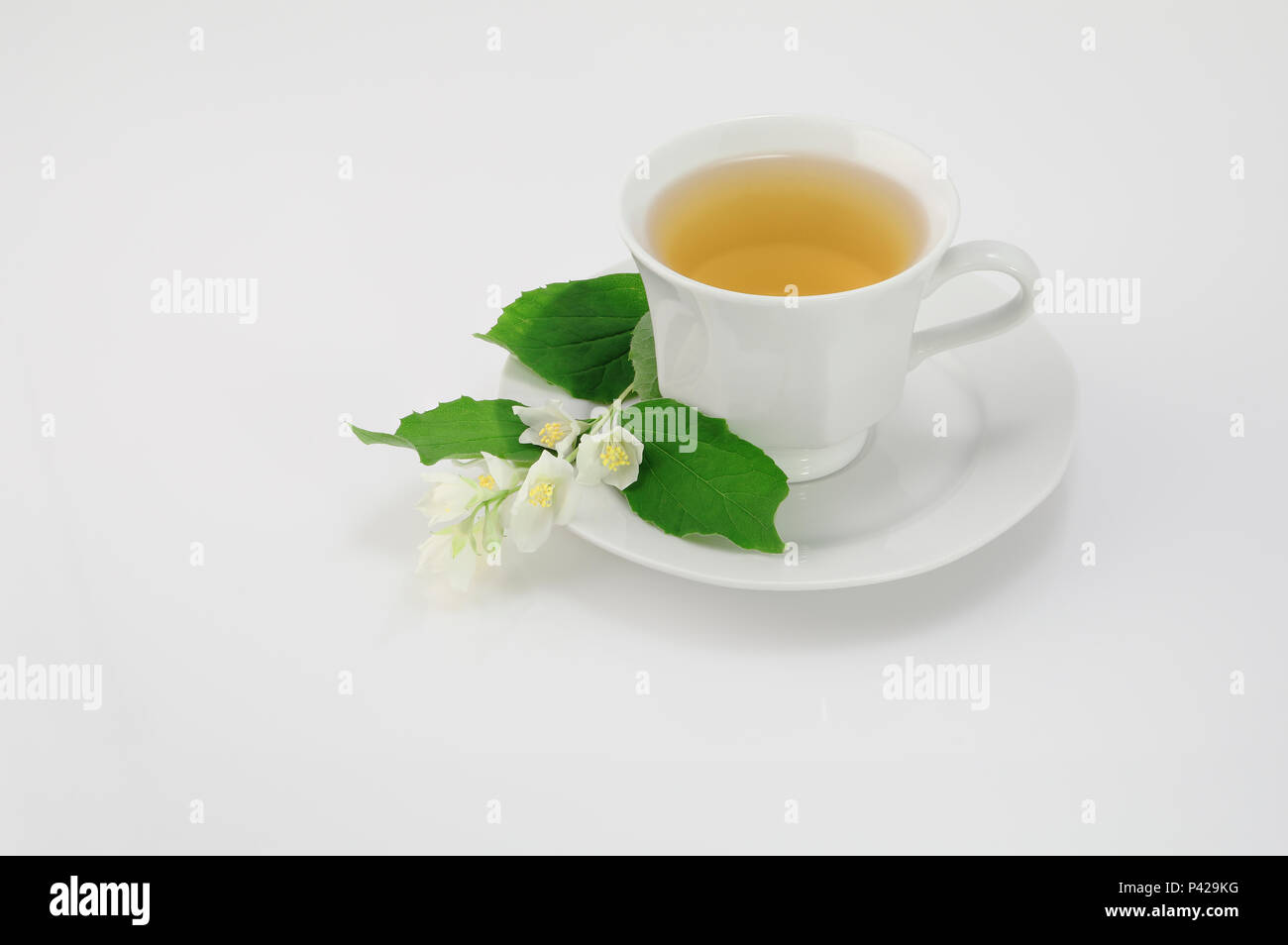 Vetro bianco tazza di tè verde con fiori di gelsomino su sfondo bianco con copia spazio. Foto Stock