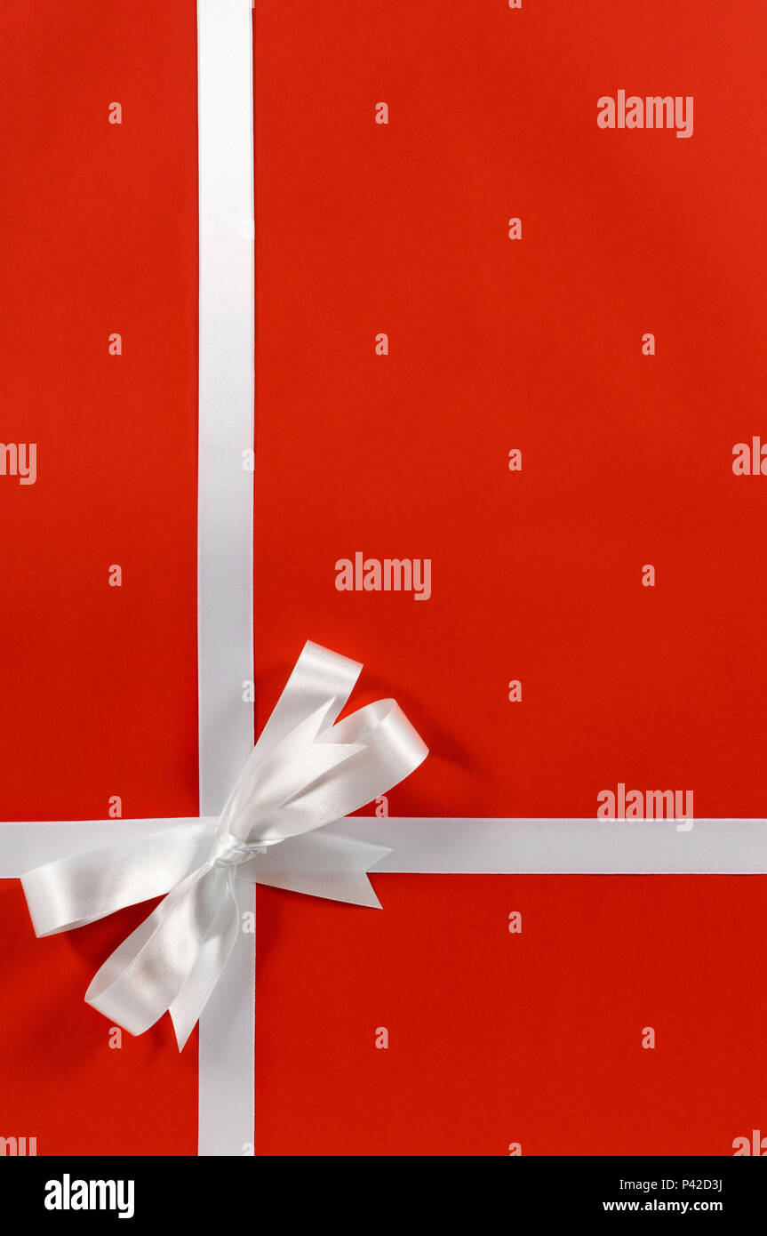 Bordo di Natale regalo telaio nastro in raso bianco su carta rossa verticale di sfondo Foto Stock