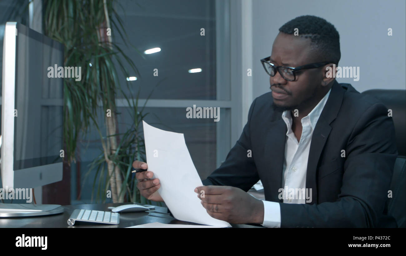 Imprenditore africano facendo lavori di carta, il calcolo di finanziare le fatture in ufficio Foto Stock