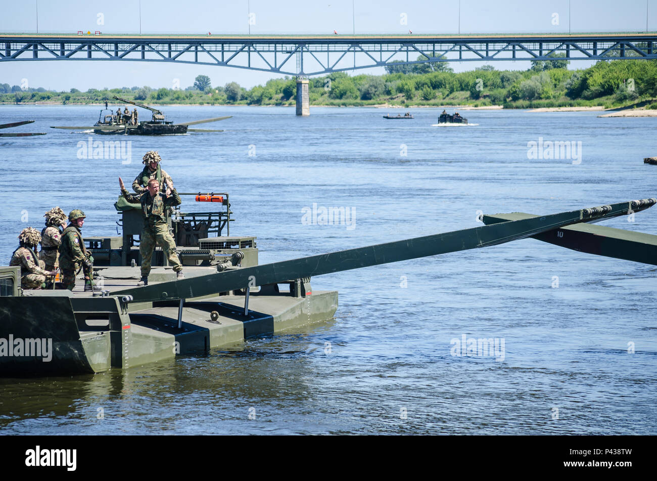 Un soldato tedesco utilizza la mano e il braccio segnali per coordinare il gruppo di un frettoloso ponte sul fiume Vistola durante un ponte che attraversa il funzionamento in Chelmno, Polonia, 7 giugno 2016. Forze multinazionali coordinati, assemblato e quindi attraversato un ponte costituito da tedesco e inglese M3 Rig anfibio, permettendo che i veicoli per attraversare il fiume come una parte di esercizio Anakonda 2016. Il polacco-led esercizio è un collettivo sforzo di formazione per rafforzare l'interoperabilità e rafforzare i legami tra gli alleati della NATO e partner, collettivo per garantire la pace e la sicurezza nella regione. Foto Stock