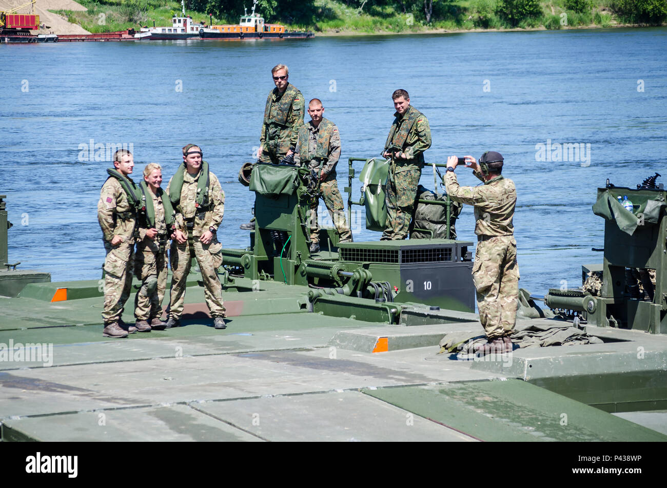 Inglesi e soldati tedeschi in pausa per l'opportunità di scattare foto durante un ponte che attraversa il funzionamento in Chelmno, Polonia, 7 giugno 2016. Forze multinazionali coordinati, assemblato e quindi attraversato un ponte costituito da tedesco e inglese M3 Rig anfibio, permettendo che i veicoli per attraversare il fiume Vistola come una parte di esercizio Anakonda 2016. Il polacco-led esercizio è un collettivo sforzo di formazione per rafforzare l'interoperabilità e rafforzare i legami tra gli alleati della NATO e partner, collettivo per garantire la pace e la sicurezza nella regione. Foto Stock