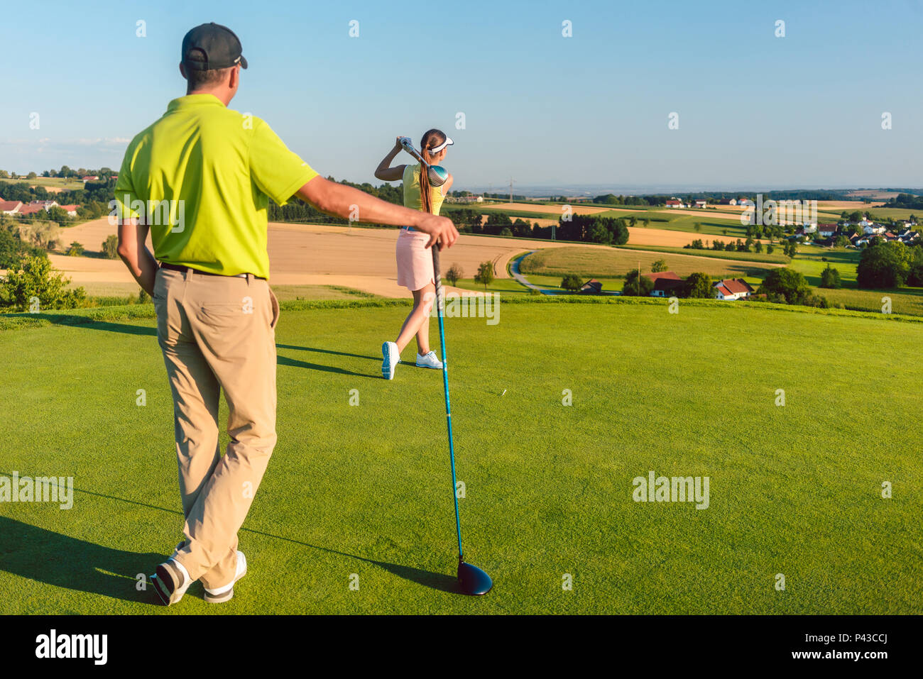 L'uomo guarda il suo partner che colpisce la palla durante la partita sul campo da golf Foto Stock