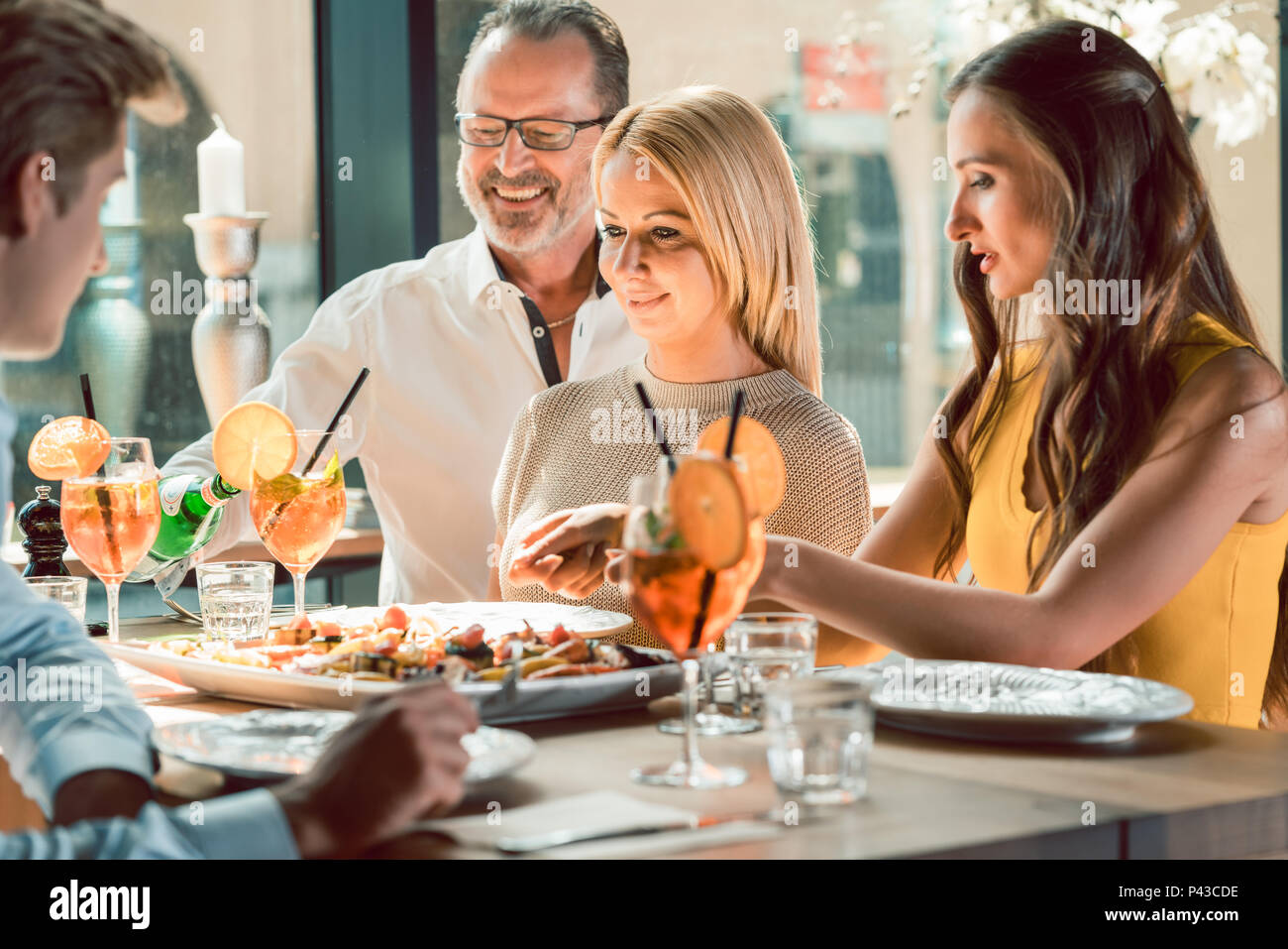 Bionda bella donna a pranzo con i suoi migliori amici presso un ristorante alla moda Foto Stock