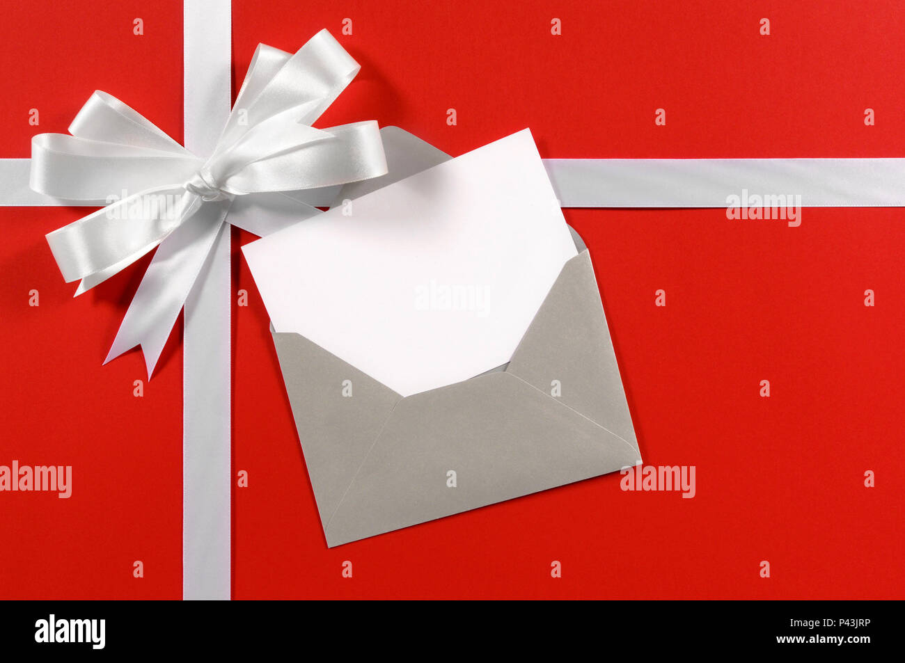 Natale carta regalo con nastro e fiocco in raso bianco su rosso sfondo  della carta d'argento con la busta e il messaggio vuoto card Foto stock -  Alamy