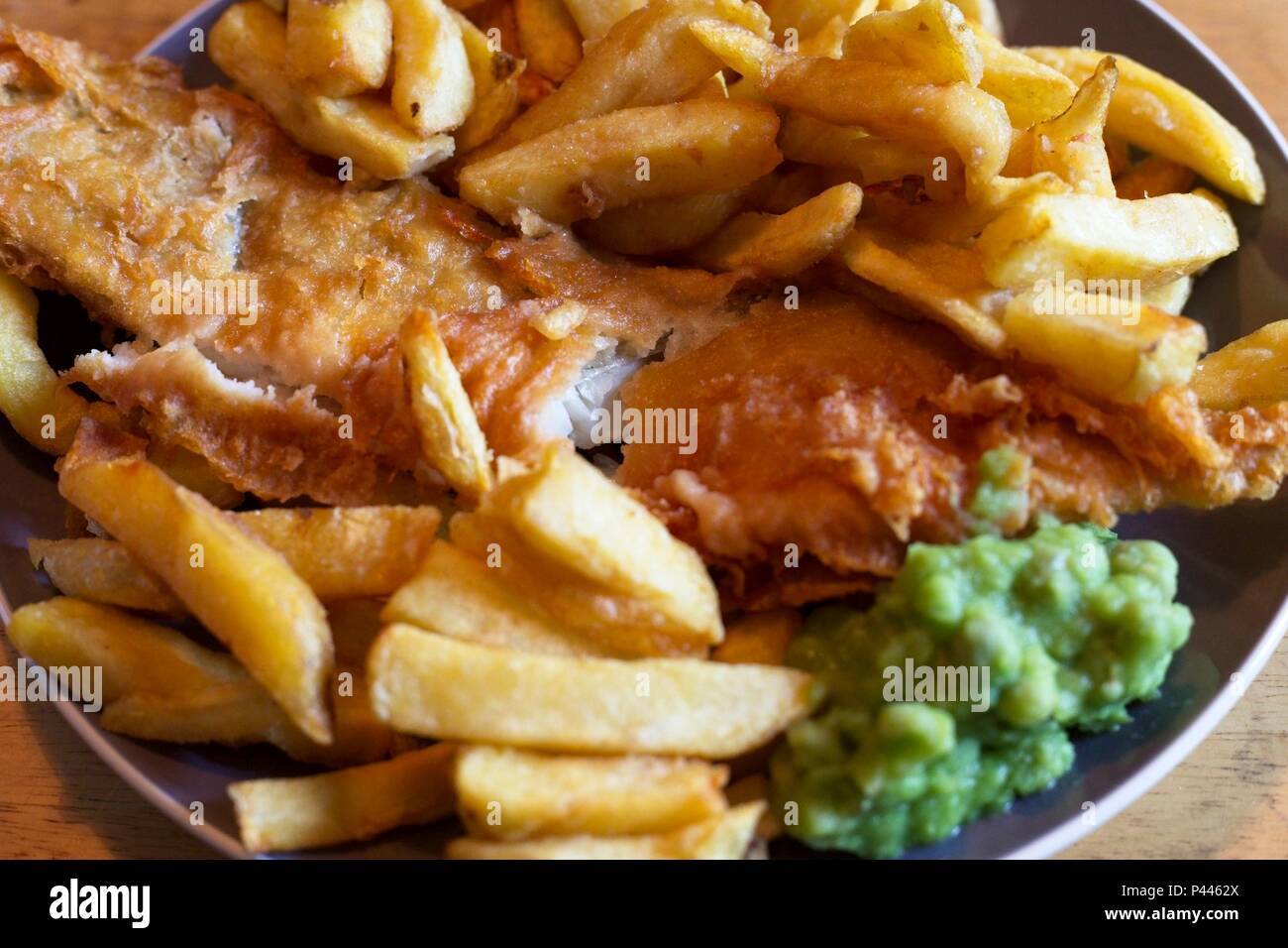 Pesce e patatine, un tradizionale pasto inglese costituito da fritte di merluzzo e patatine con fiacco piselli Foto Stock
