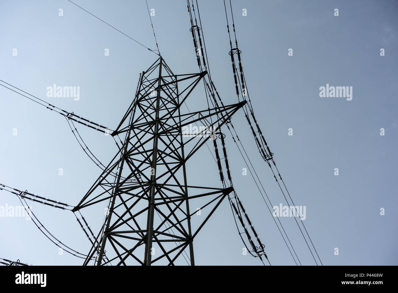 Power Tower polo industriale per l'elettricità, chiudere fino a nuvoloso cielo scuro a basso angolo di visione Foto Stock