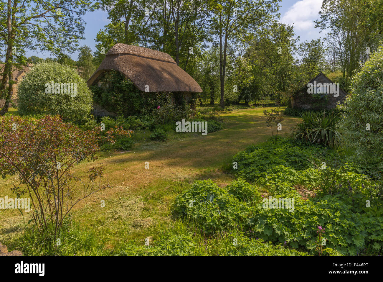 Cottage con il tetto di paglia a fianco del Fiume Coln a Winston, Gloucestershire Foto Stock