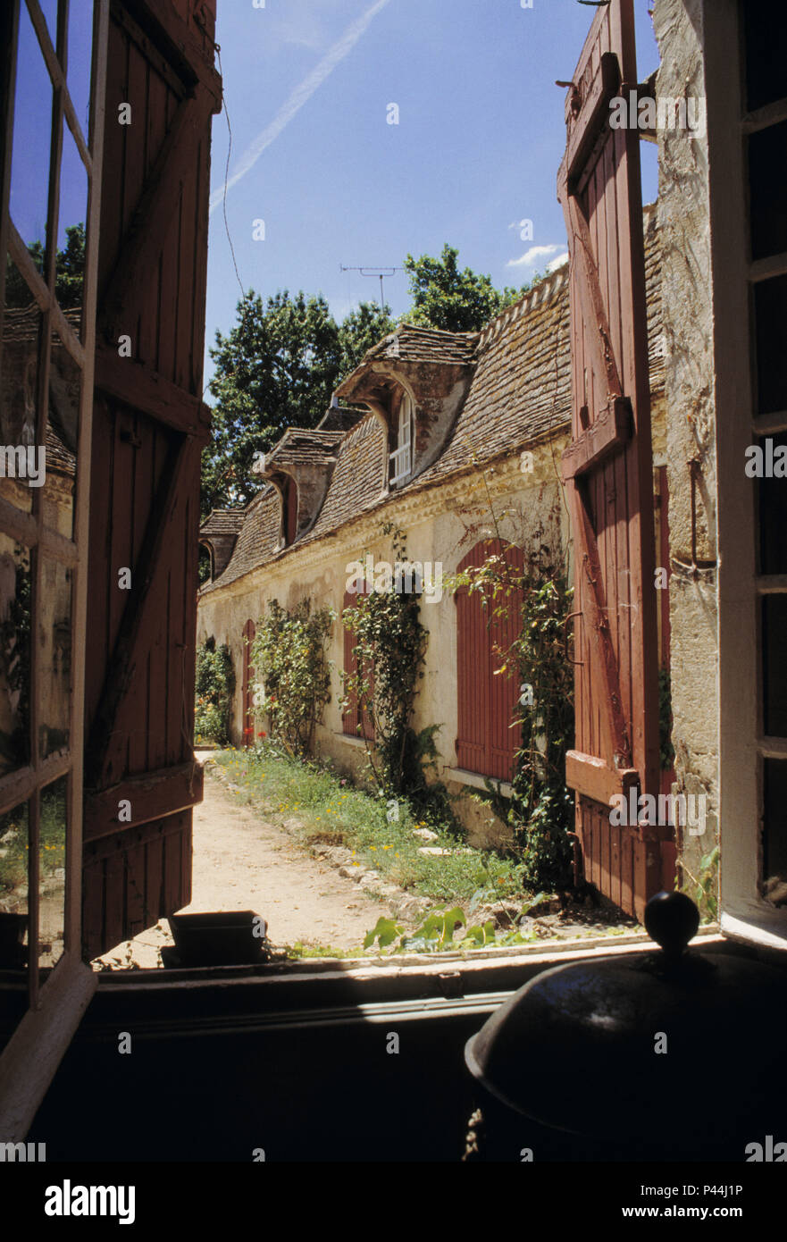 Finestra con persiane di legno e vista della dépendance della Casa francese di campagna Foto Stock