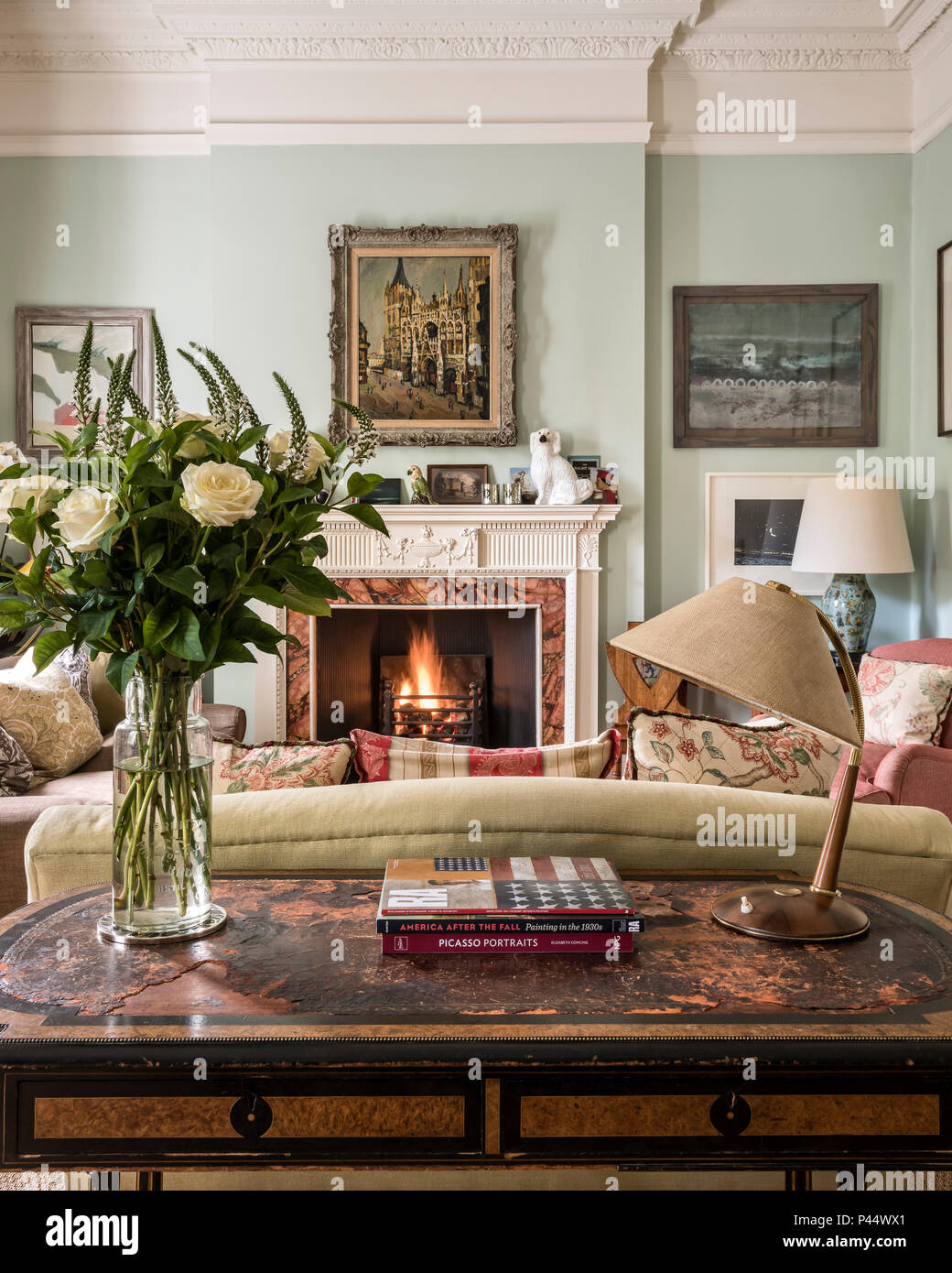 Lampada Vintage sulla tavola con incorniciato artwork e acceso il fuoco Foto Stock