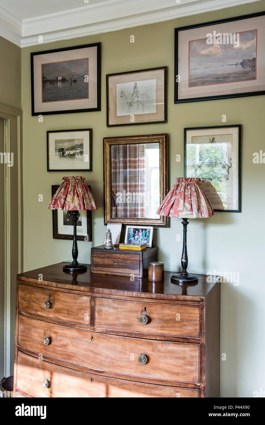 La raccolta di opere d'arte incorniciata sopra torace vintage con lampade Foto Stock