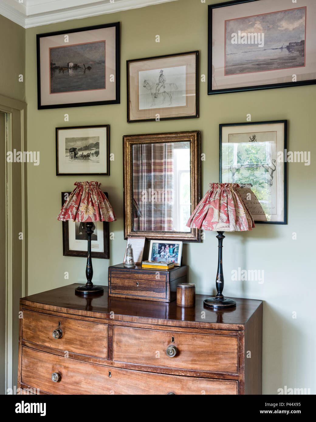 La raccolta di opere d'arte incorniciata sopra torace vintage con lampade Foto Stock