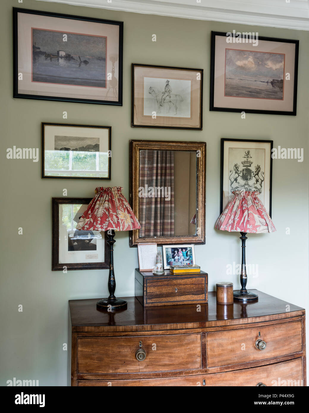 La raccolta di opere d'arte incorniciata sopra torace vintage con lampade Foto Stock